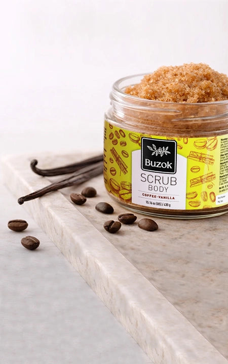 Jar of Buzok coffee vanilla body scrub with vanilla beans and coffee beans on a light surface.